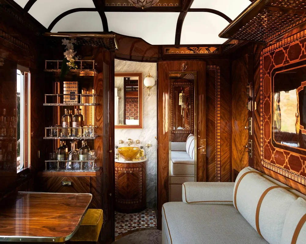 A wood-panelled train salon with a velvet sofa, inlaid marquetry and a small bar