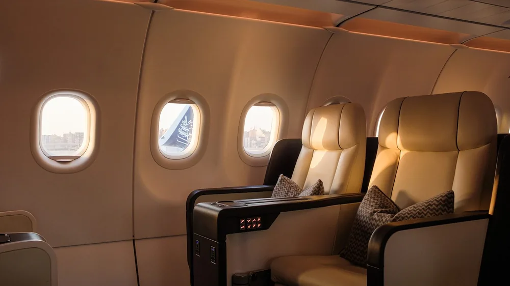 Cream leather flatbed seats beside oval windows in the cabin of the Four Seasons Private Jet