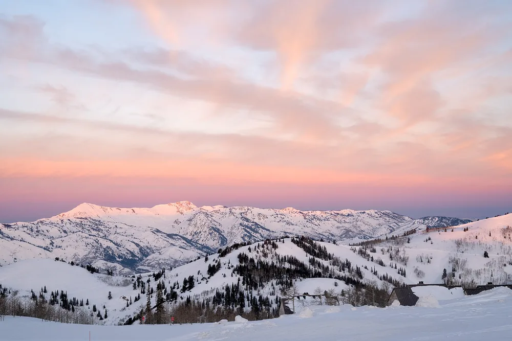 First light turns the sky pink over the snowfields and ridges of Powder Mountain, Utah